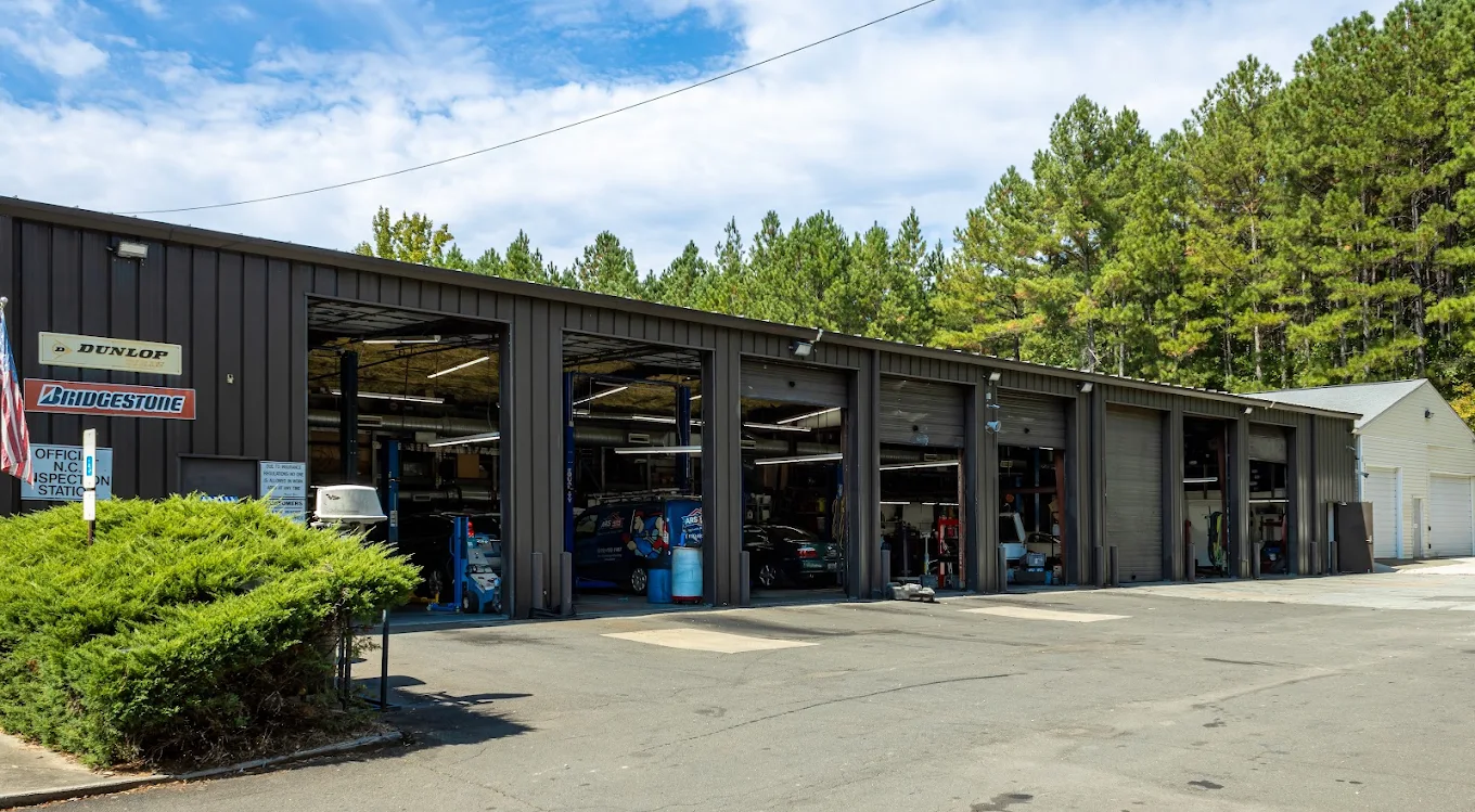 Couch Automotive Repair service bays with garage doors open, cars on lifts, at 4260 Bennett Memorial Rd, Durham, NC